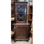 An oak two section corner cupboard with single glazed door over single door base,