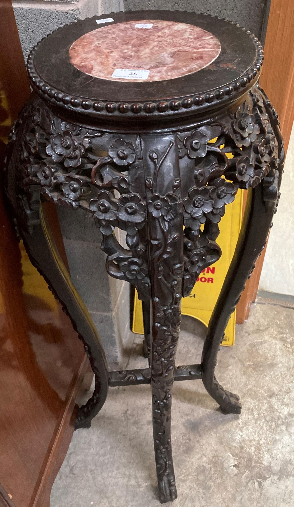 A Chinese peony carved hardwood jardiniere stand with an inset circular marble top 93cm high and