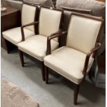 A set of three mahogany framed armchairs with cream vinyl seats and backs.