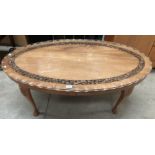 An oval carved mahogany coffee table on cabriole legs with glass preserve 120cm x 62cm