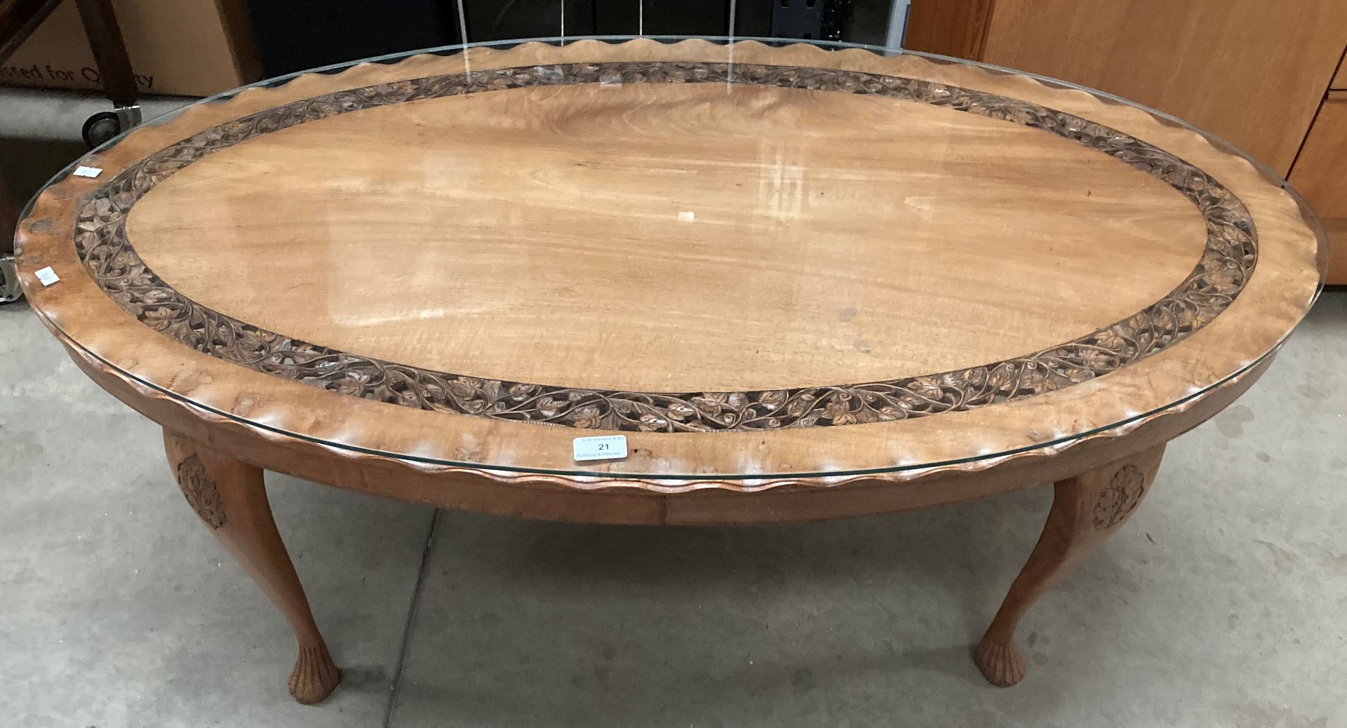 An oval carved mahogany coffee table on cabriole legs with glass preserve 120cm x 62cm