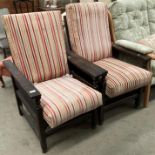 A pair of oak framed armchairs with red, orange and pink fabric seats and backs.