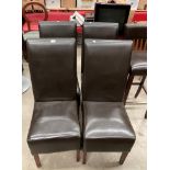 A set of four dark brown leather effect upholstered dining chairs.