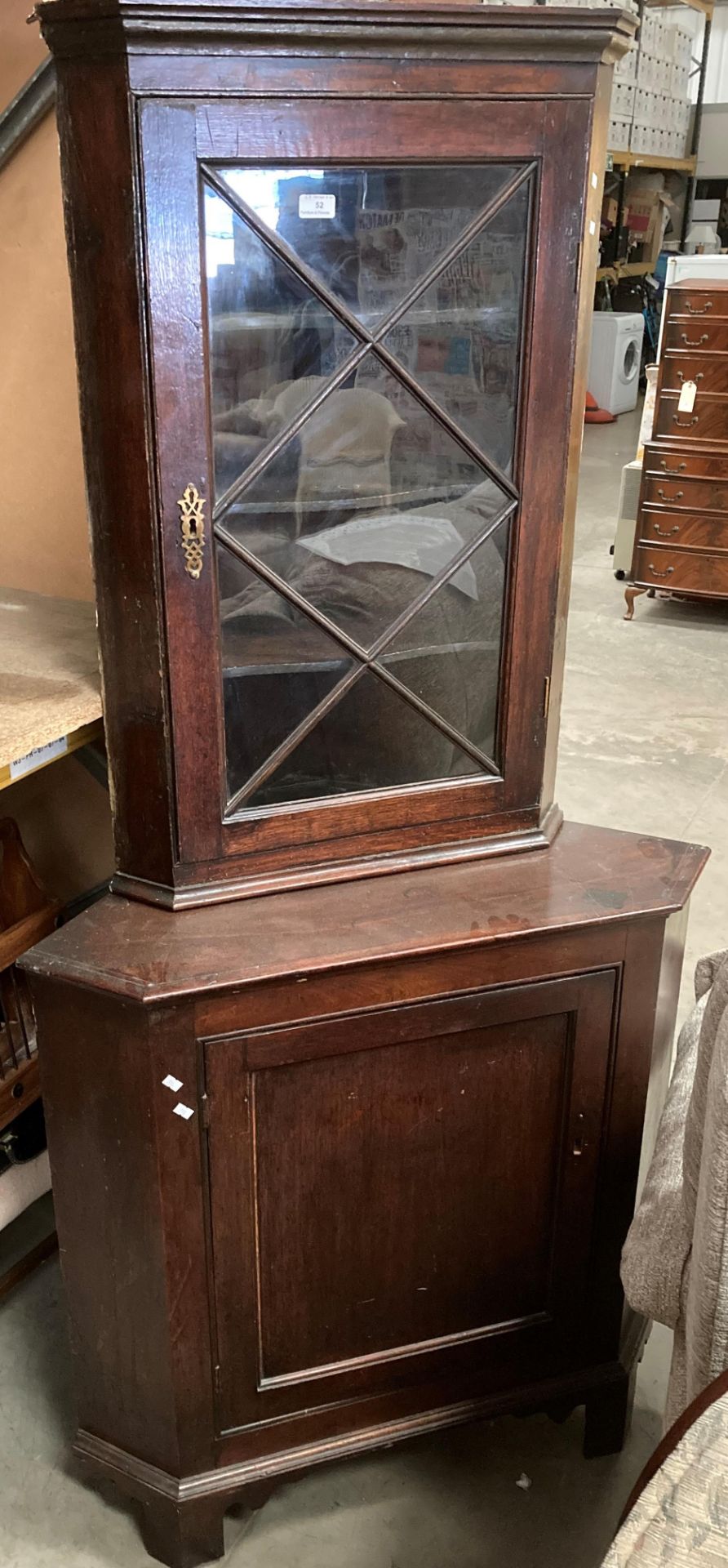 An oak two section corner cupboard with single glazed door over single door base,