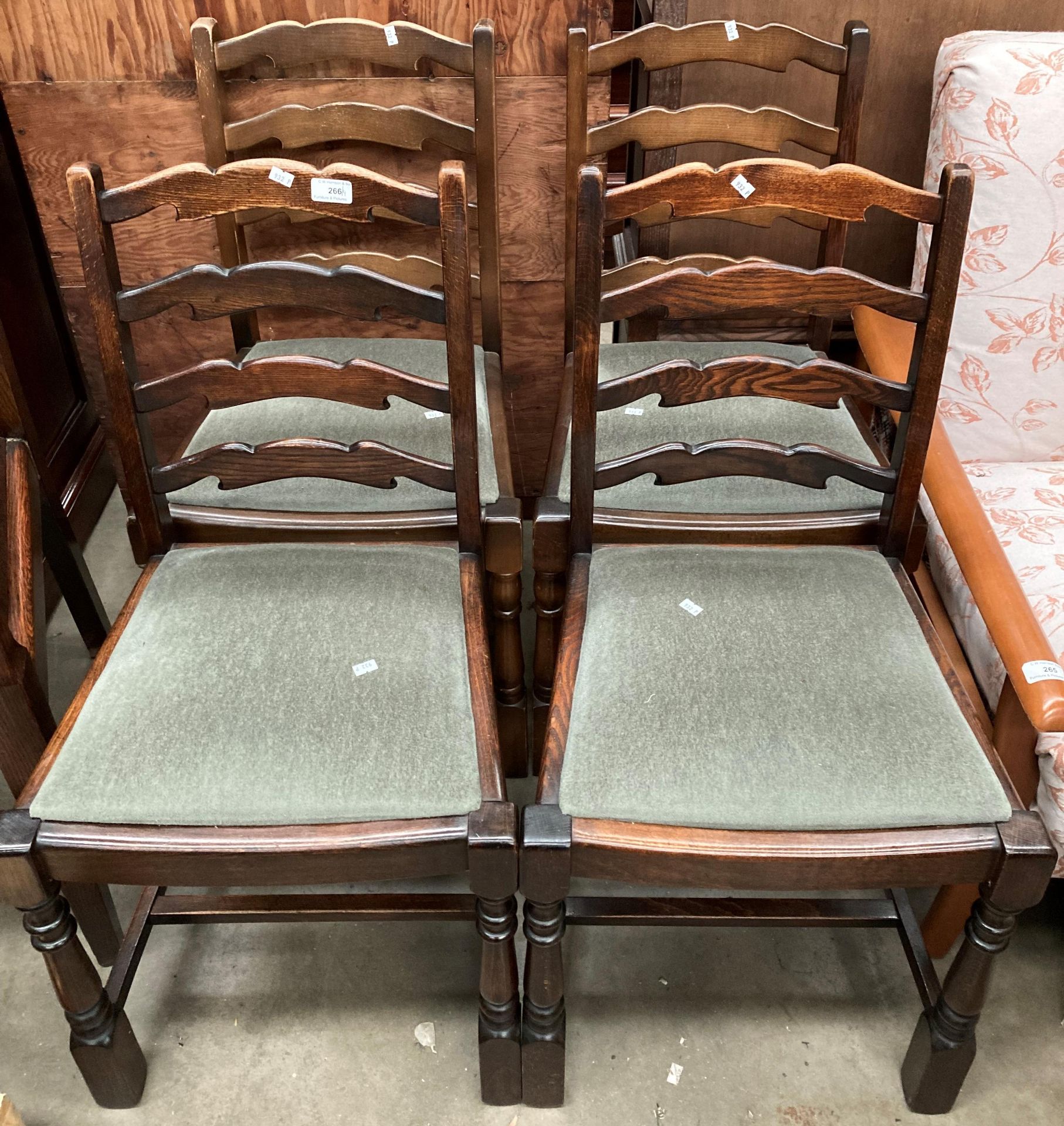 A set of four oak ladder back dining chairs with green fabric seats.