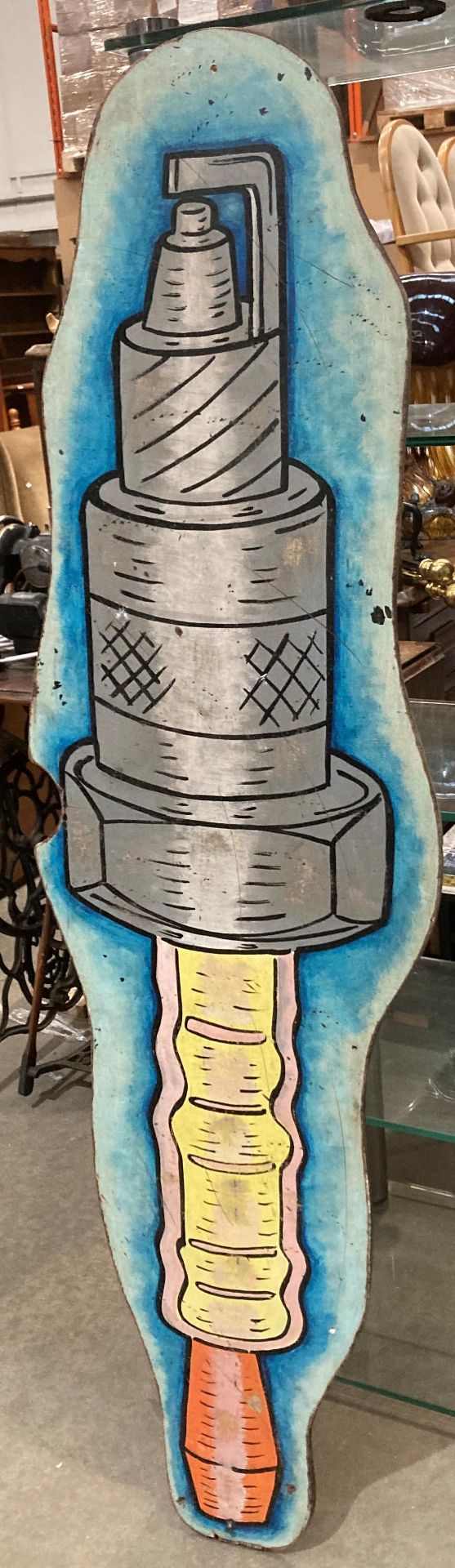 A reproduction painted sign on plywood of a spark plug,