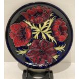 A Moorcroft blue ground anemone patterned plate, 26cm diameter.