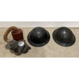 A pair of black plastic military helmets and a military gas mask (for display purposes only)