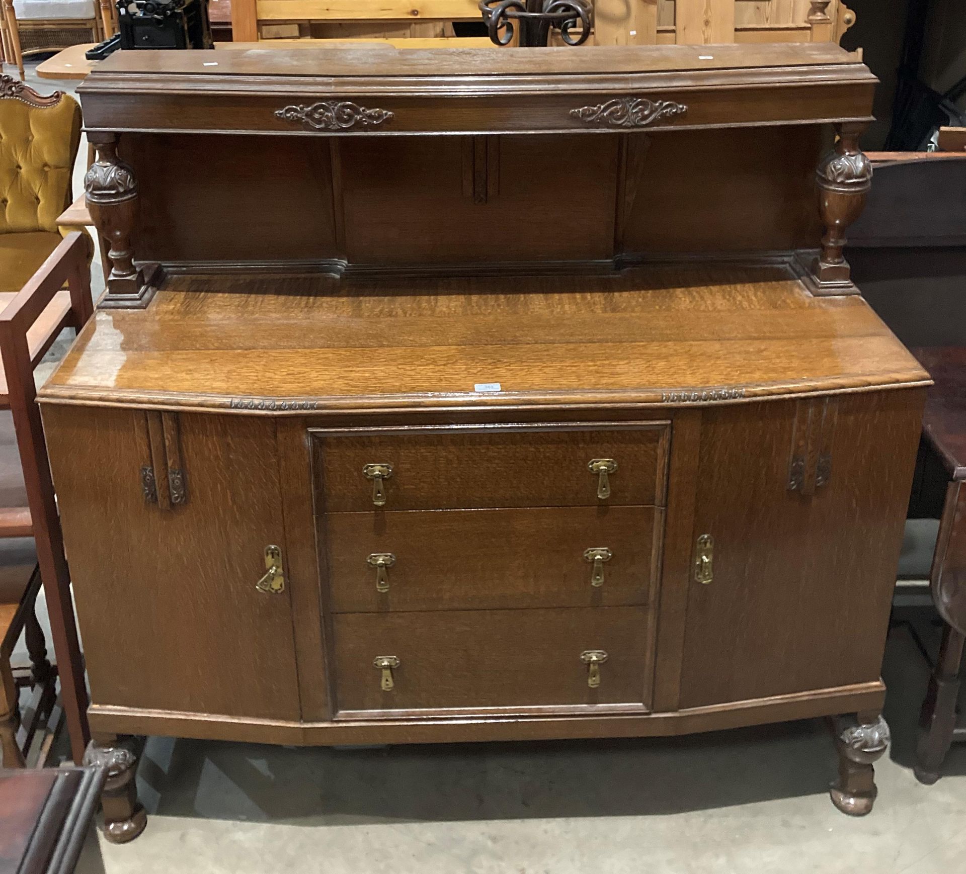 An oak sideboard with three central drawers and two cupboards,