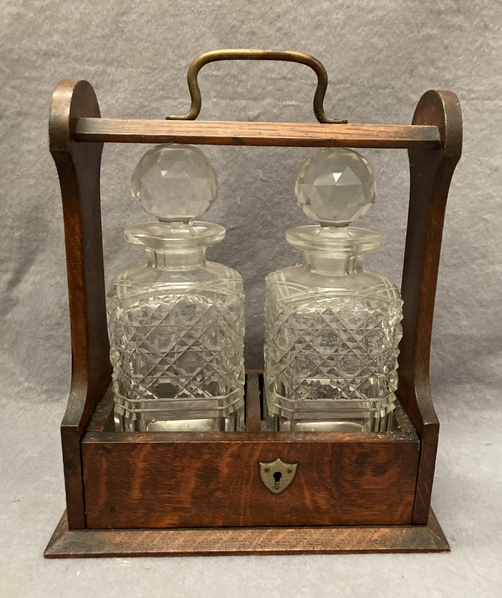 An oak two decanter tantalus, locked,
