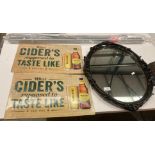 A black painted oval framed wall mirror, 60cm x 45cm, two modern metal wall signs 'Thatchers Cider',