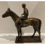 A metal sculpture with bronze effect finish of a Jockey on a racehorse with stamp to base 'Quist'