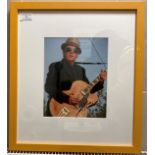 A signed colour photograph of Elvis Costello in yellow frame (slight scratches to frame) 26cm x