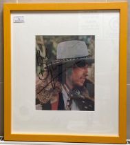 A signed album cover of Bob Dylan 26cm x 20cm in yellow frame complete with a signed note from