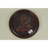 A carved walnut circular wall plaque of Dickens