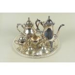 A silver plated four piece tea set on a tray with a pair of plated candlesticks