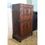 An early 20th Century Korean twin door two part cupboard on stand with applied brass wear