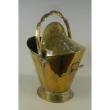 A late 19th Century brass helmet coal scuttle with embossed floral and wrythen handle