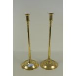 A pair of tall late 18th Century brass candlesticks with slender stems and dished circular bases,