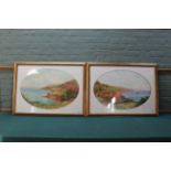A pair of watercolours of large coastal landscapes in oval mounts,