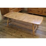 A blonde Ercol beech and elm coffee table on tapered legs with stretcher under tier