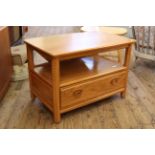 An Ercol blonde beech and elm low one drawer side table with drop leaf to back and carved detailing