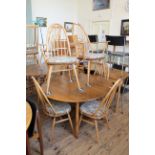 An Ercol blonde beech and elm drop leaf dining table and six chairs including two carvers