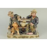 A large Capodimonte figurine of two inebriated elderly gentlemen on a park bench