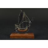 A white metal model of a ship on wooden stand