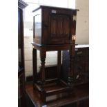 A Jacobean style carved oak small cupboard on stand with linen fold carved door