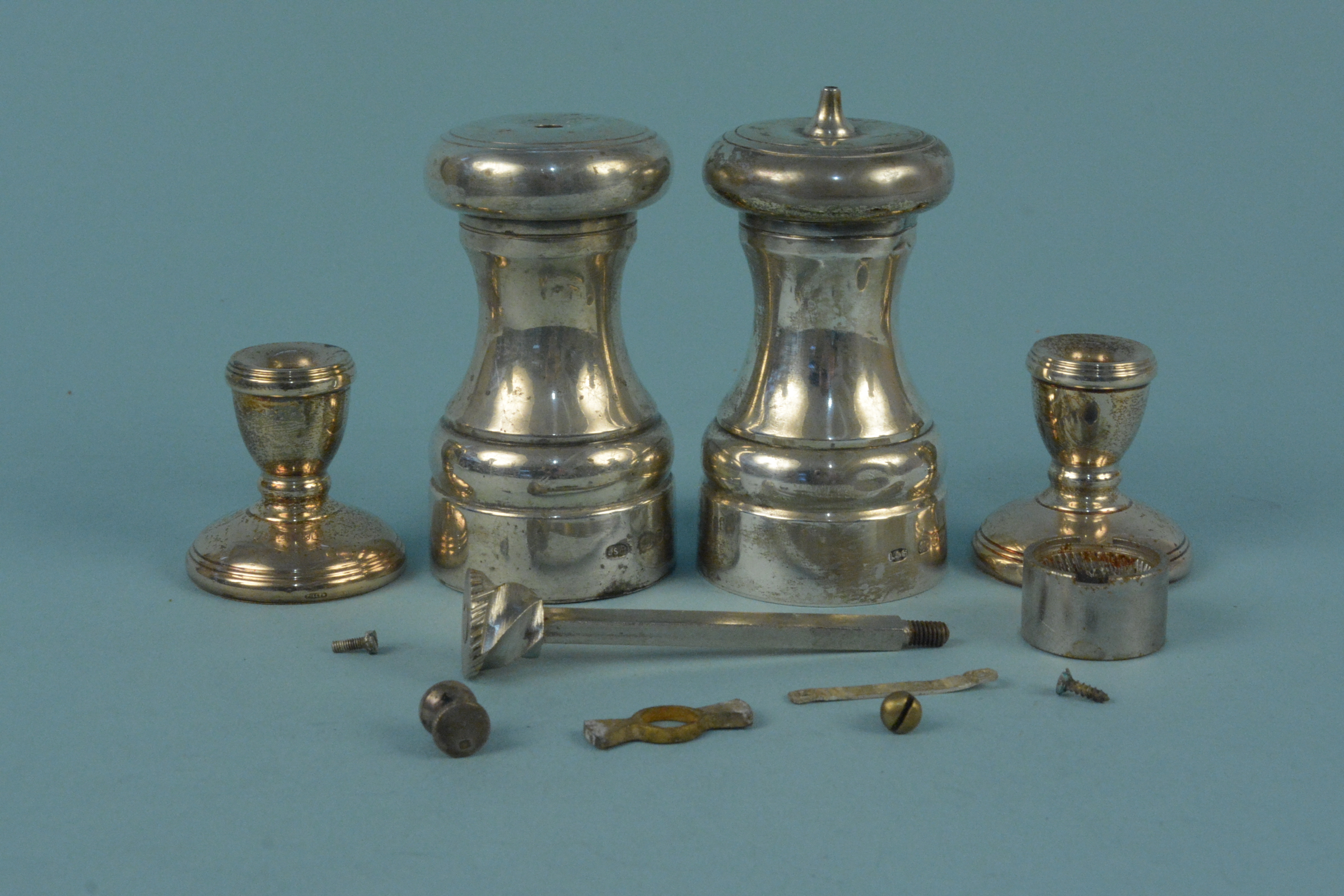 A silver pepper mill (as found), a silver salt of mill form and two miniature silver candlesticks