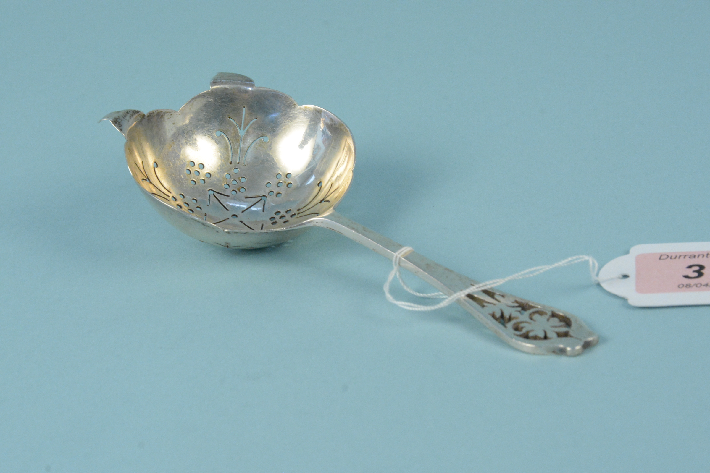 A silver tea strainer with pierced decoration to handle,
