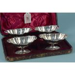 A cased set of four white metal boat shaped salt cellars with flare bases, salts are unmarked,