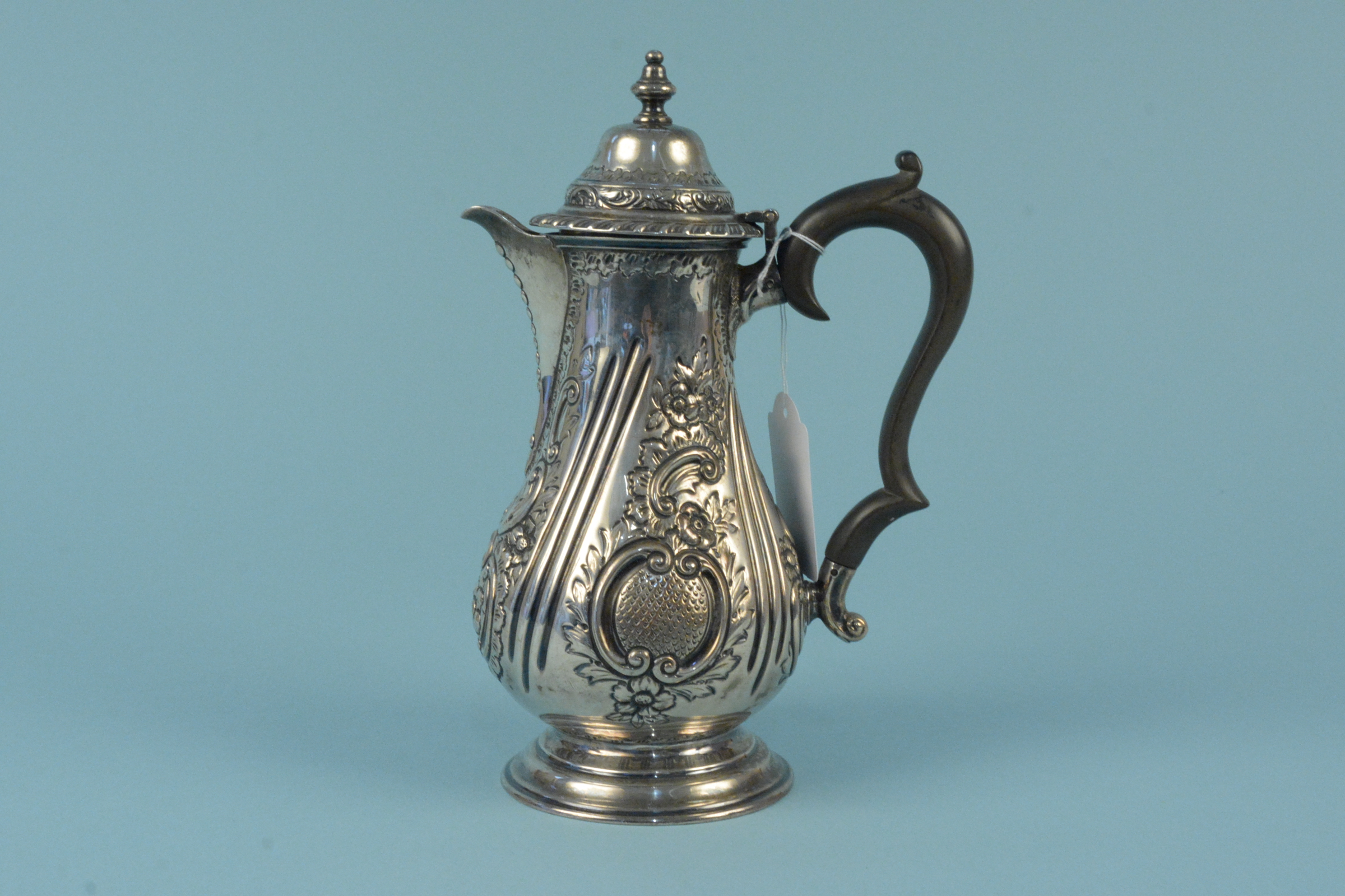 A Victorian silver coffee pot with embossed floral decoration on flared base, engraved with crest,