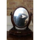 A Victorian mahogany toilet mirror with oval frame and shaped carved supports