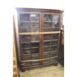 An early 19th Century oak two door glazed bookcase on offset bracket feet (one pane broken)