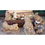 A vintage suitcase containing various garden ornaments including gnomes
