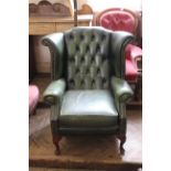 A Queen Anne style green leather button back armchair