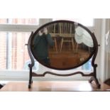 An Edwardian Sheraton style oval mahogany framed swing toilet mirror