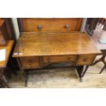 A 1950's three drawer writing table on shaped end supports