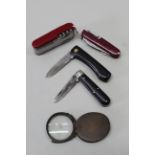 A multi-bladed/tools Victorinox Swiss knife with three other pocket knives and a 'glass'