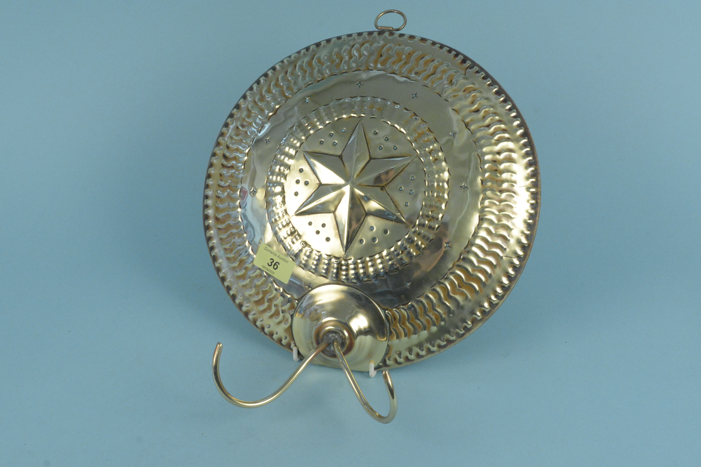 An early 19th Century twin branch circular brass wall sconce with central embossed star and circles