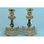 A pair of Edwardian brass candlesticks on pierced square bases and blue enamel stems with gilt