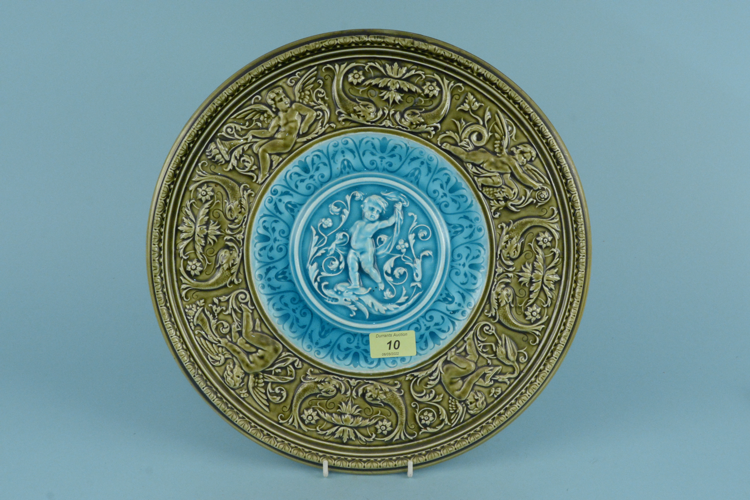 A late 19th Century Austrian Majolica wall plaque with a green moulded border enclosing a central