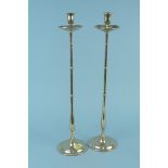 A pair of tall late 19th Century brass candlesticks with drip trays,