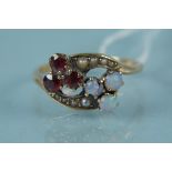 An unmarked yellow metal opal, garnet and seed pearl set ring (one opal damaged), size M,