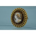 A yellow metal mounted cameo brooch with blue enamel decoration