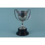 A silver presentation two handled trophy cup with embossed and engraved decoration,
