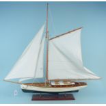 A large gaff rigged wooden model boat with linen sails and mounted on wooden base,