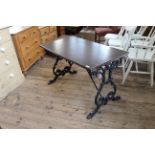 A cast iron pub table with stained mahogany top